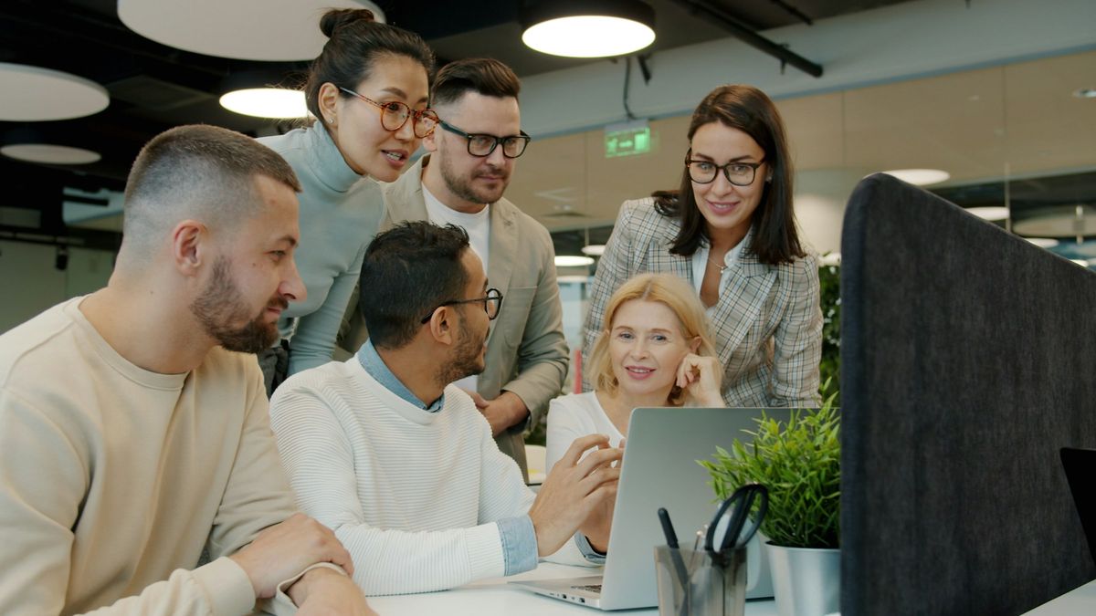 Un equipo reunido alrededor de una laptop en una oficina, mirando la pantalla